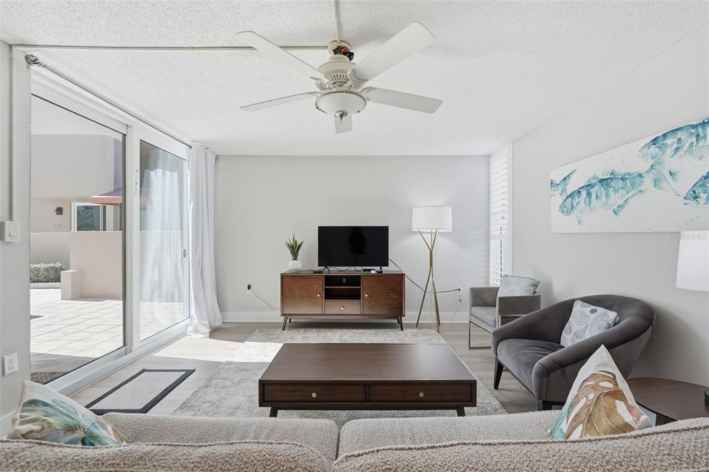 A living room features a ceiling fan, a television on a wooden console, and seating — 632 EDGEWATER DRIVE UNIT 135, DUNEDIN, FL