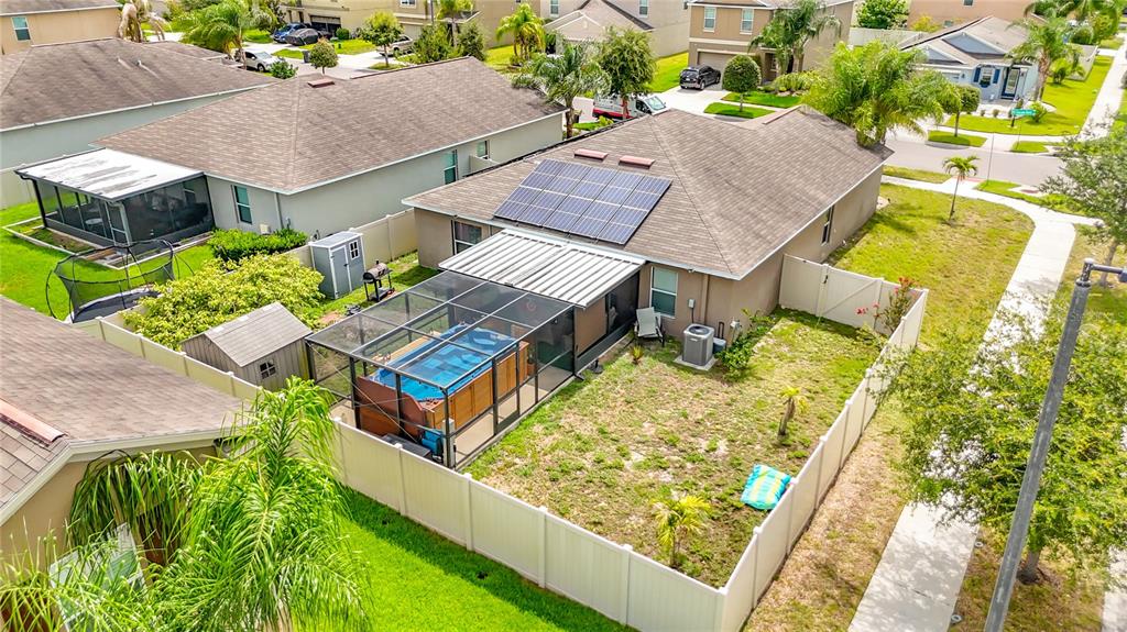 An aerial view shows a house with solar panels, a screened-in pool, and a fenced yard — 102 CASCADE BEND DRIVE, RUSKIN, FL
