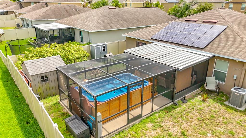 An aerial view shows a backyard with a screened-in swim spa and solar panels — 102 CASCADE BEND DRIVE, RUSKIN, FL