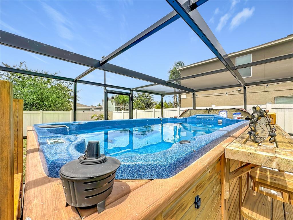 A blue swim spa sits on a wooden deck inside a screened-in outdoor enclosure — 102 CASCADE BEND DRIVE, RUSKIN, FL