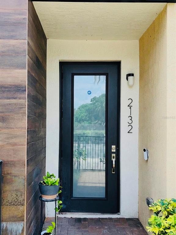 A black front door with a glass panel is set between a wood-paneled wall and stucco — 2132 NW 6TH STREET, FORT LAUDERDALE, FL