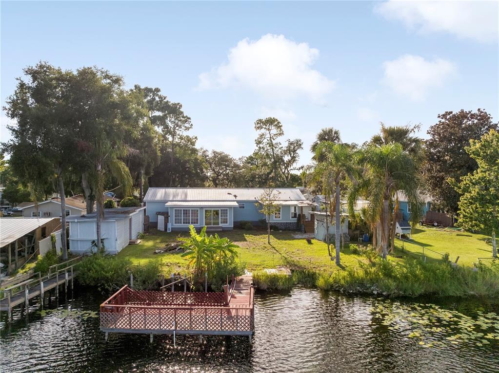 A blue house with a metal roof sits on a grassy lot by a lake — 36112 LAKE UNITY ROAD, FRUITLAND PARK, FL