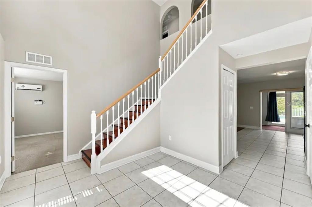 A tiled entryway features a staircase with wooden treads and white railings leading to a landing — 507 GRANITE CIR, CHULUOTA, FL