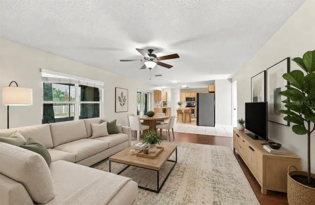 A living room with a sectional sofa, coffee table, television, and an open-concept dining area — 507 GRANITE CIR, CHULUOTA, FL