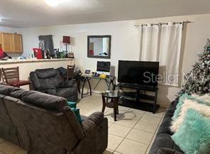 A living room features a dark sofa, a television on a stand, and a computer desk — 1603 ROSE LANE, EUSTIS, FL