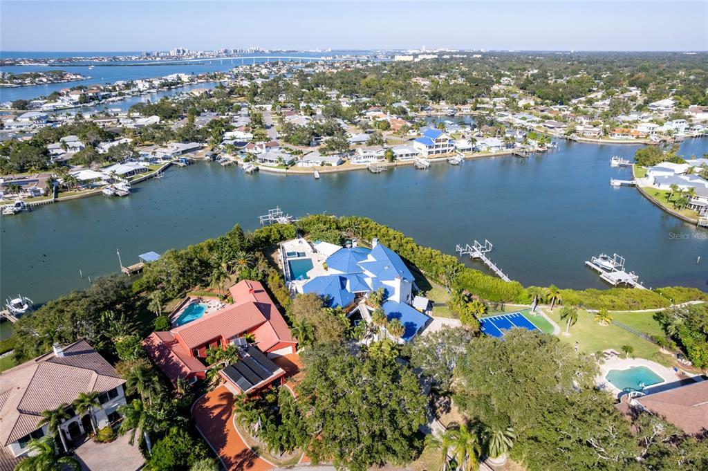 An aerial view shows a waterfront estate with multiple pools and blue-roofed buildings — 2268 KINGS POINT DRIVE, LARGO, FL