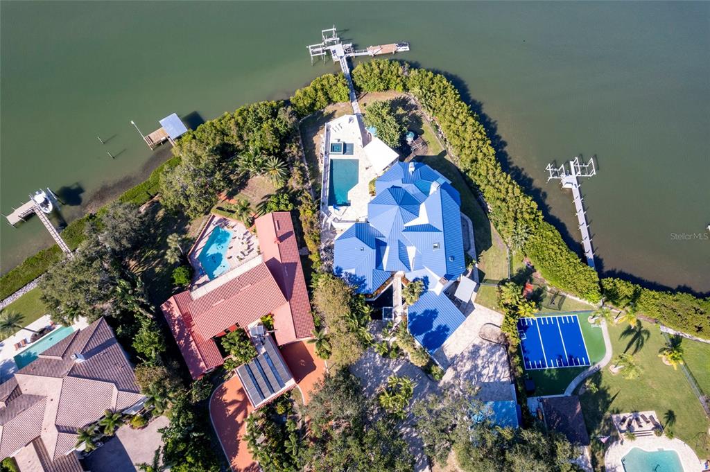 An aerial view shows a waterfront estate with multiple pools, blue roofs, and private docks — 2268 KINGS POINT DRIVE, LARGO, FL