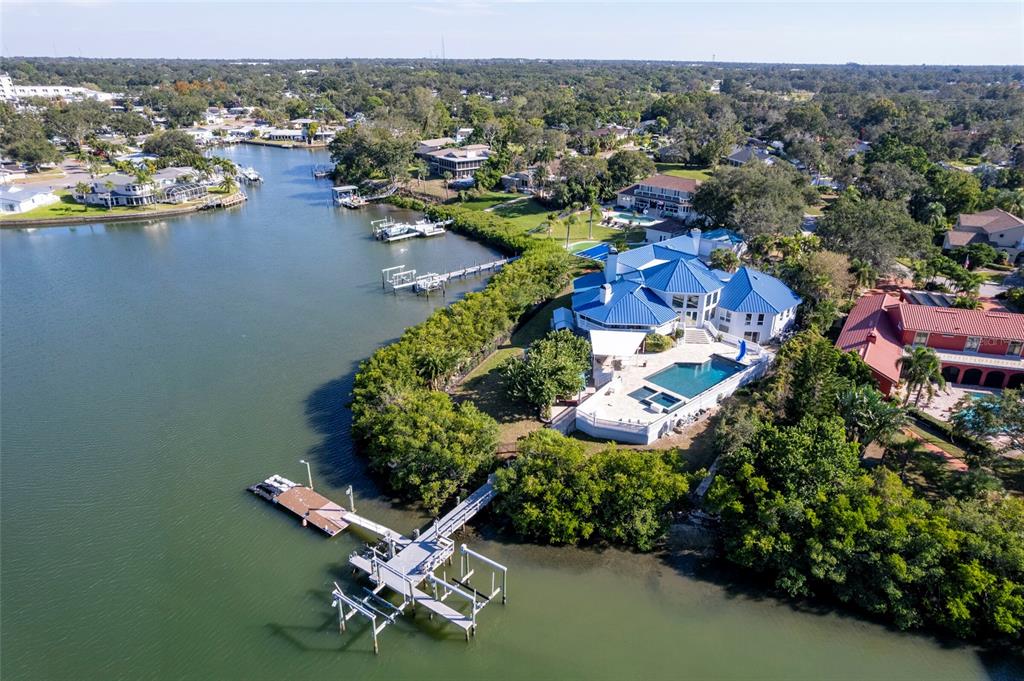 An aerial view of a waterfront house with a blue roof, pool, and private dock — 2268 KINGS POINT DRIVE, LARGO, FL