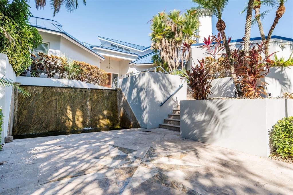 A stone patio with a star inlay features a waterfall wall and stairs leading upward — 2268 KINGS POINT DRIVE, LARGO, FL