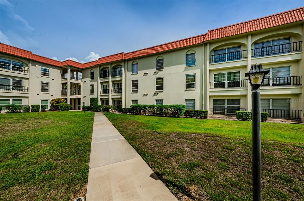 A multi-story apartment building with a red tile roof and a concrete walkway — 2700 BAYSHORE BOULEVARD UNIT 2201, DUNEDIN, FL