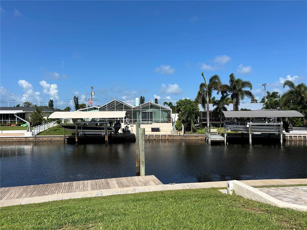 A canal-front view showing two boat lifts with boats and houses in the background — 4528 NASSAU ROAD, BRADENTON, FL