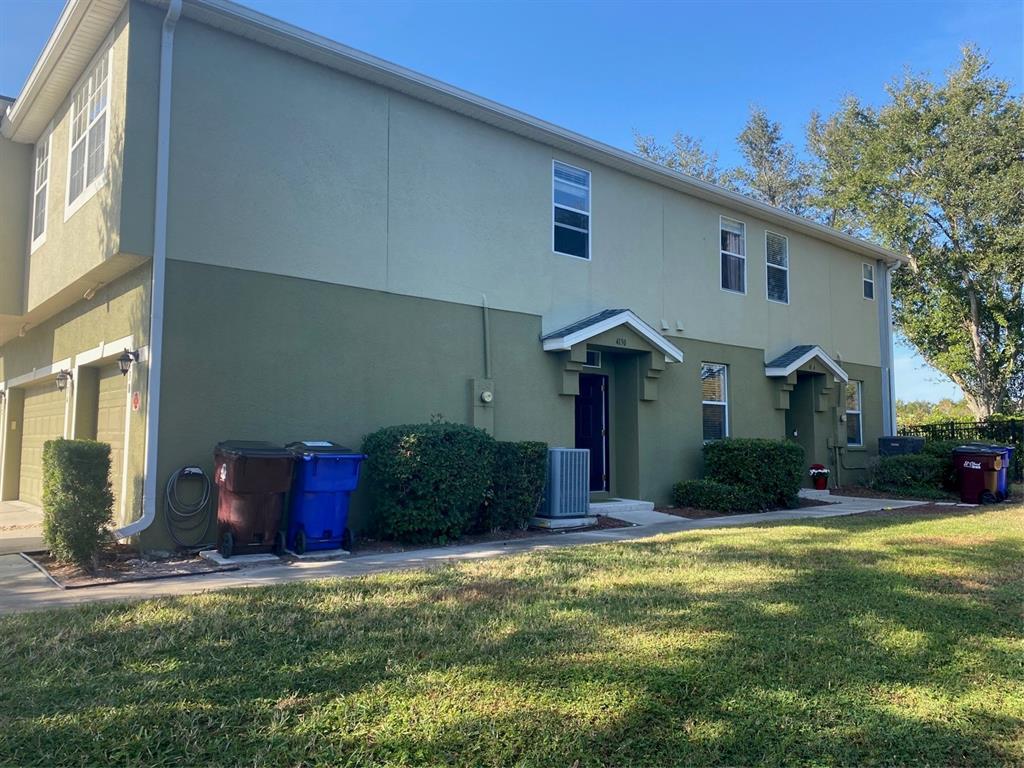 A two-story townhouse exterior with a green facade, two front entrances, and a grassy lawn — 4130 ORANGE TREE COURT, ST CLOUD, FL