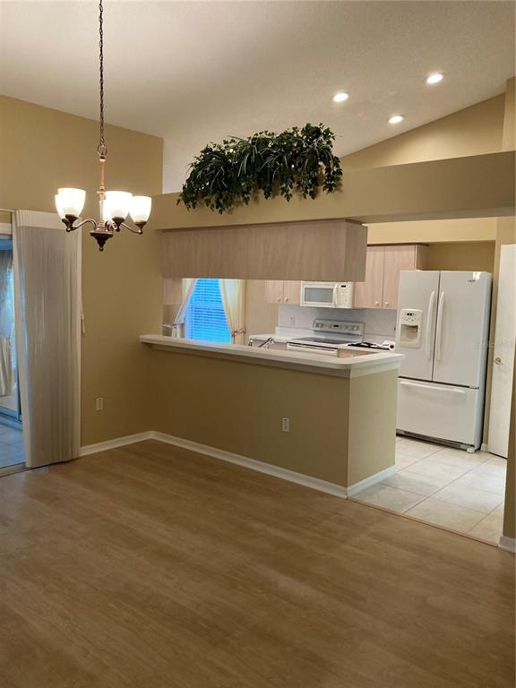 A dining area with a chandelier opens to a kitchen with white appliances and cabinets — 1327 TOLLBRIDGE COURT, TRINITY, FL
