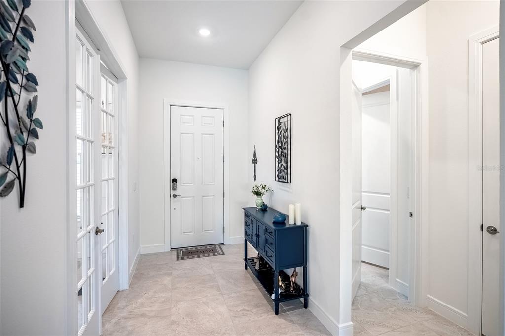 A bright entryway features a white front door, tile flooring, and a blue console table — 6107 SW 86TH CIRCLE, OCALA, FL