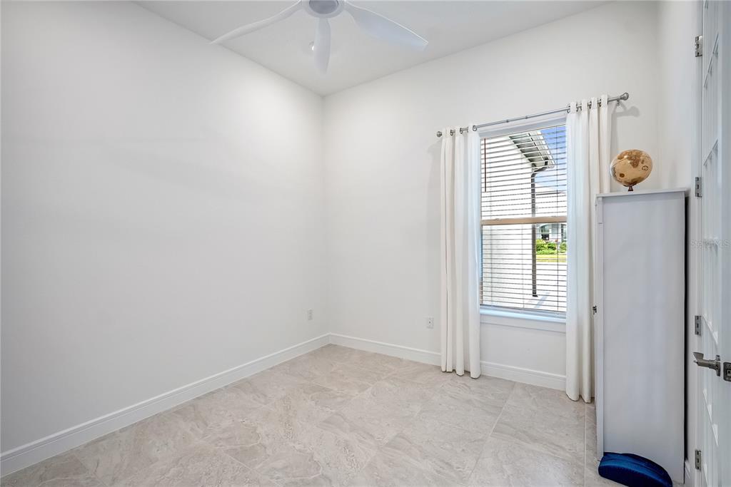 A small, empty room with white walls, tile flooring, a ceiling fan, and a window — 6107 SW 86TH CIRCLE, OCALA, FL