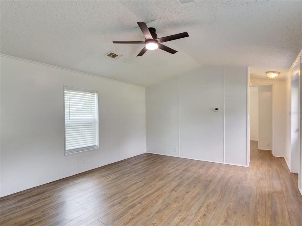 An empty room with white walls, wood-look flooring, and a ceiling fan — 26007 HECKMAN DRIVE, BROOKSVILLE, FL