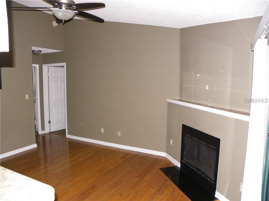 A living room features hardwood floors, a fireplace with a mantel, and a ceiling fan — 8722 MALLARD RESERVE DRIVE UNIT 204, TAMPA, FL