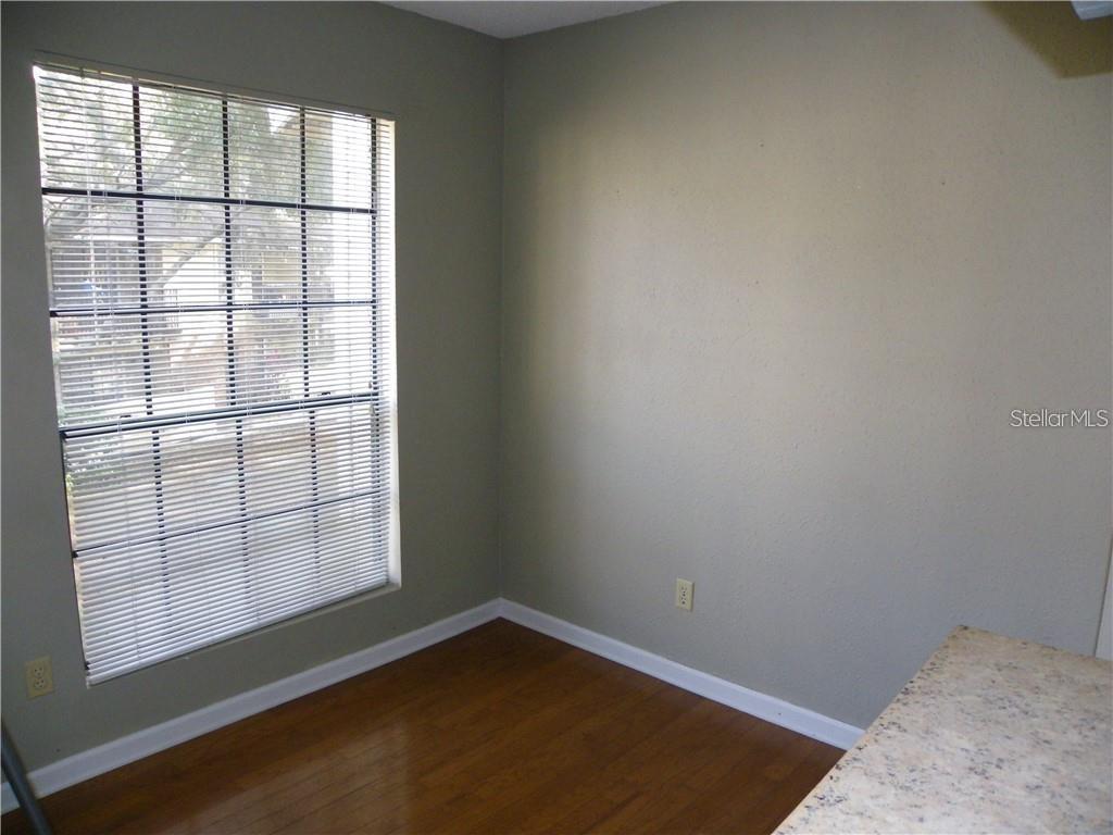 A room with hardwood floors, a large window with blinds, and light-colored walls — 8722 MALLARD RESERVE DRIVE UNIT 204, TAMPA, FL