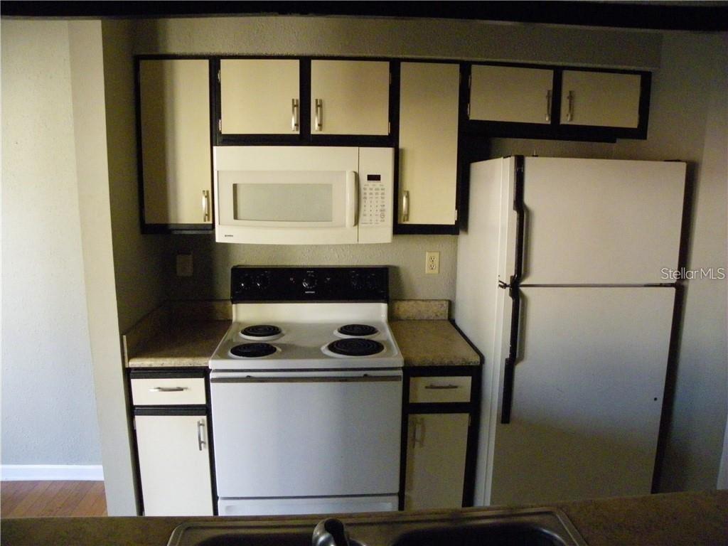 A kitchen features white appliances, light-colored cabinets with dark trim, and a laminate countertop — 8722 MALLARD RESERVE DRIVE UNIT 204, TAMPA, FL