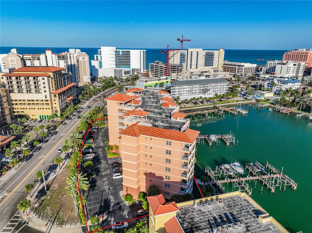 An aerial view shows a multi-story hotel building with a parking lot and boat docks — 530 S GULFVIEW BOULEVARD UNIT 500, CLEARWATER, FL