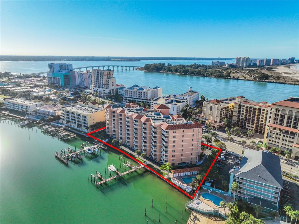 An aerial view shows a waterfront condominium complex with a pool and boat docks — 530 S GULFVIEW BOULEVARD UNIT 500, CLEARWATER, FL
