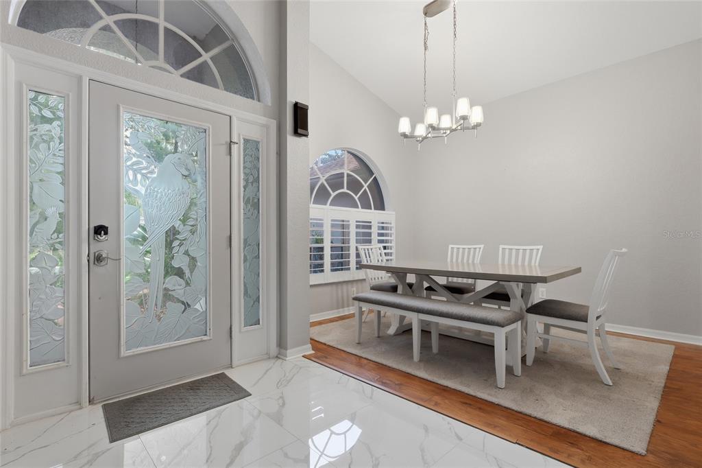 A dining area with a white table and chairs sits on a rug near an entryway — 2208 KATANA PLACE, BRANDON, FL