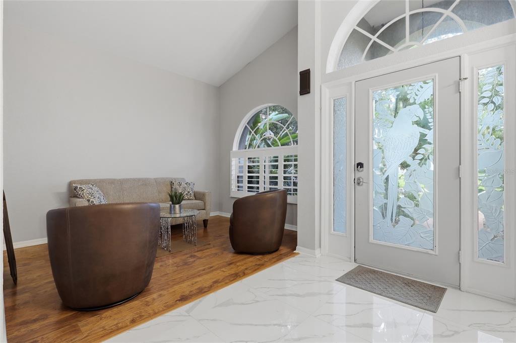 An entryway with white marble floors transitions to wood flooring in a seating area — 2208 KATANA PLACE, BRANDON, FL