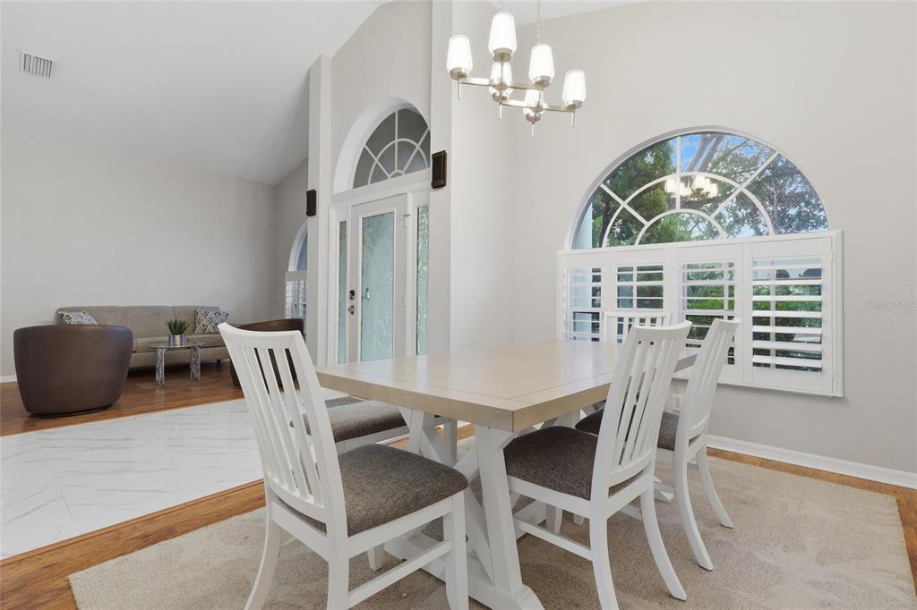 A dining area features a white table with chairs, a chandelier, and arched windows — 2208 KATANA PLACE, BRANDON, FL