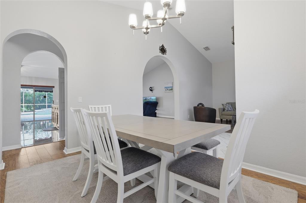 A dining room features a light wood table, white chairs, and arched doorways leading to other rooms — 2208 KATANA PLACE, BRANDON, FL