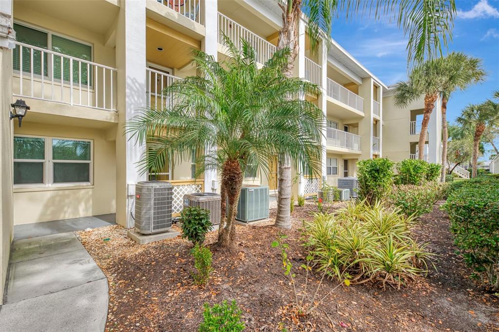 Exterior view of a multi-story apartment building with palm trees and air conditioning units — 433 CERROMAR LANE UNIT 341, VENICE, FL