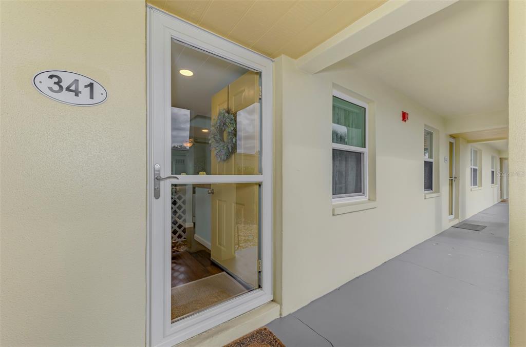 A view of a building exterior walkway featuring a front door labeled 341 — 433 CERROMAR LANE UNIT 341, VENICE, FL