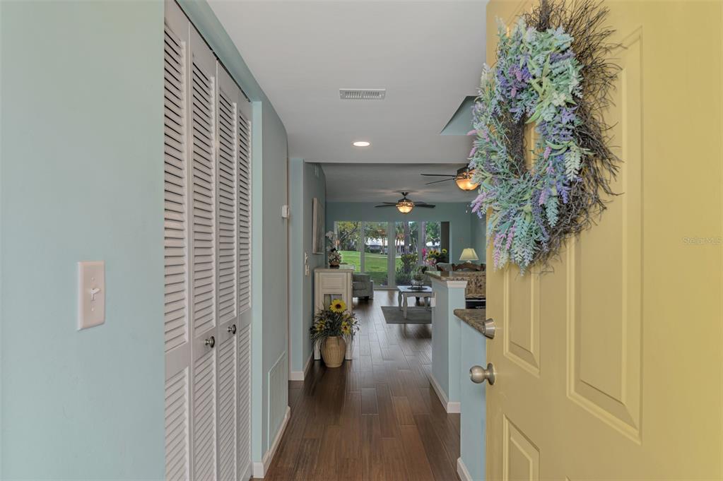A view from a yellow front door into a hallway with light blue walls — 433 CERROMAR LANE UNIT 341, VENICE, FL