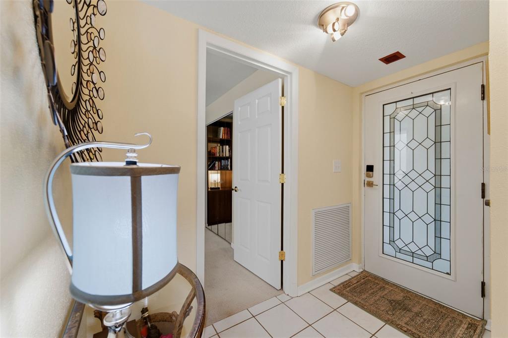 An entryway features a white front door with decorative glass, tile flooring, and a table lamp — 2775 KIPPS COLONY DRIVE S UNIT 305, GULFPORT, FL
