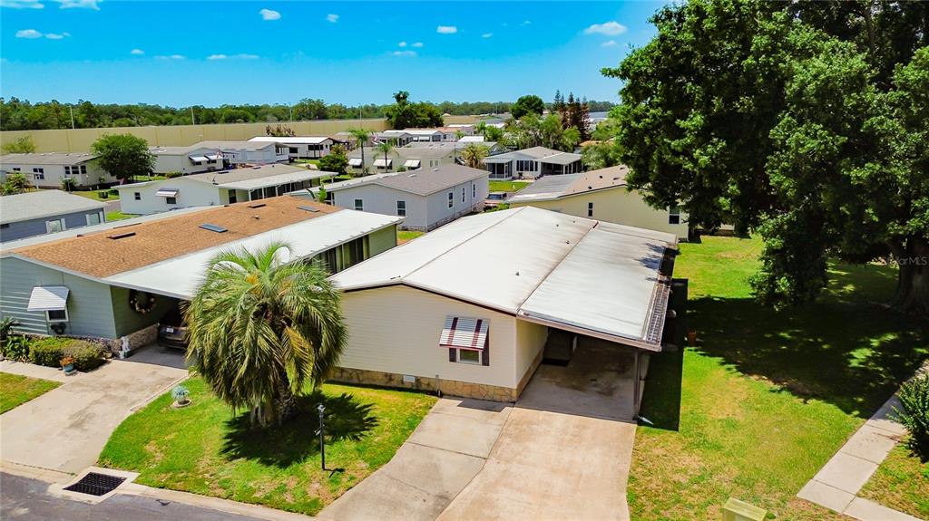 A single-story mobile home with a concrete driveway, carport, and stone-patterned skirting — 4424 BRAVE LANE, ST CLOUD, FL