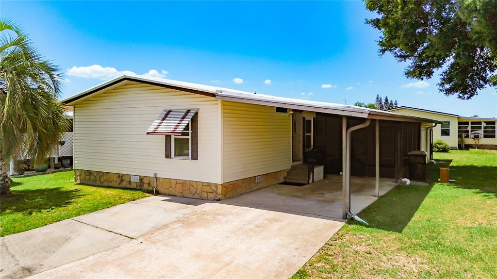 An elevated exterior view shows a light-colored mobile home with a carport and palm tree — 4424 BRAVE LANE, ST CLOUD, FL