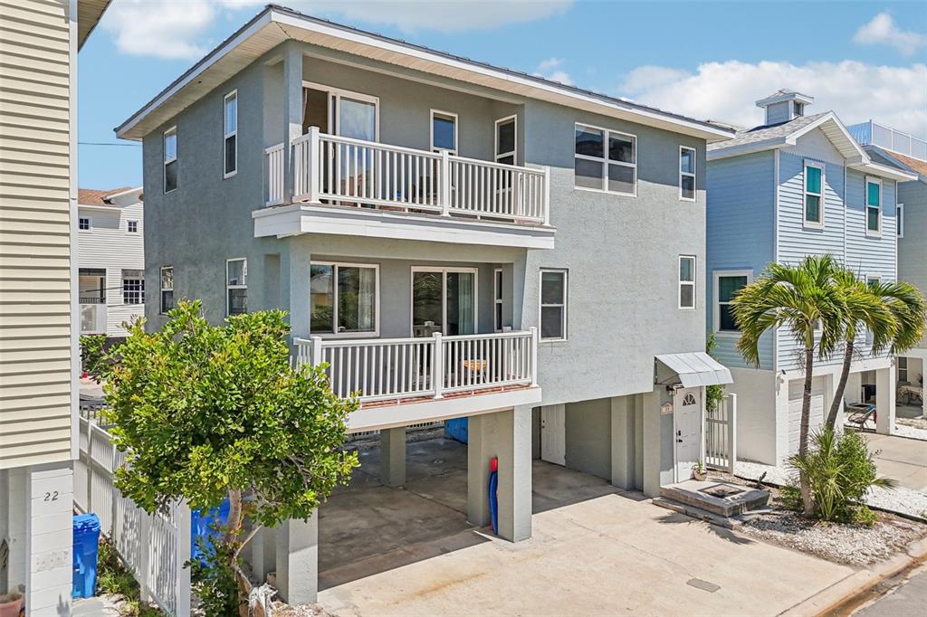 An open-concept living and dining area features terracotta tile floors, a surfboard, and kitchen — 23 80TH AVENUE, TREASURE ISLAND, FL