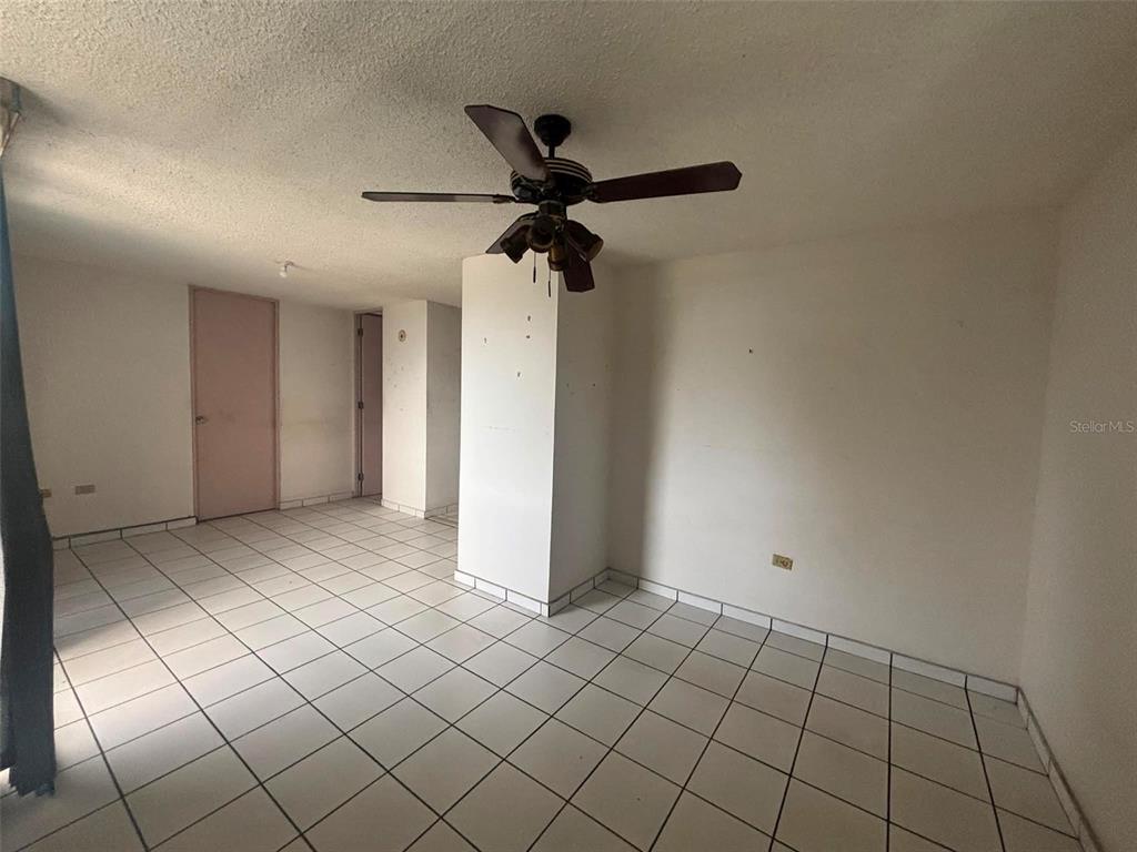 An empty room features white tiled floors, a ceiling fan, and plain white walls — 81 Mayaguez Street Apt 32 CONDO FRENCH PLAZA UNIT 327, SAN JUAN, PR
