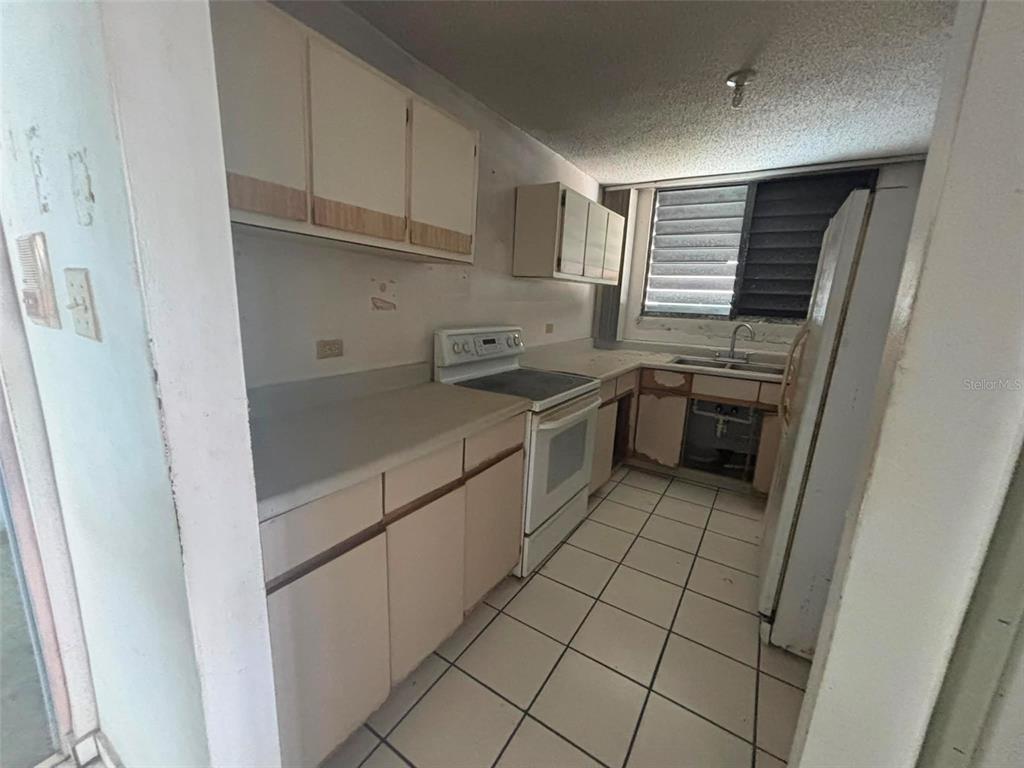 A kitchen with white cabinets, tile flooring, a white stove, and a window above the sink — 81 Mayaguez Street Apt 32 CONDO FRENCH PLAZA UNIT 327, SAN JUAN, PR