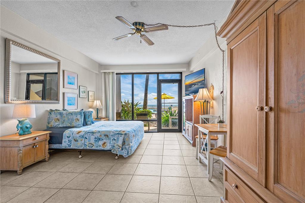 A bedroom with tile floors, a queen bed, and a sliding glass door overlooking the beach — 2301 S ATLANTIC AVENUE UNIT 120, DAYTONA BEACH SHORES, FL