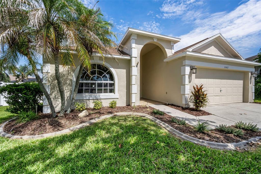 A single-story house with a beige stucco exterior, arched entryway, and a palm tree — 25427 SEVEN RIVERS CIRCLE, LAND O LAKES, FL