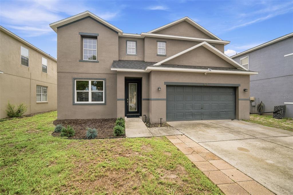 A two-story house with a gray stucco exterior, a two-car garage, and a front walkway — 428 CHIMNEY ROCK DRIVE, RUSKIN, FL