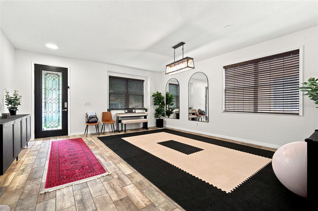 A room with wood-look tile flooring, a large exercise mat, two arched mirrors, and a chandelier — 428 CHIMNEY ROCK DRIVE, RUSKIN, FL