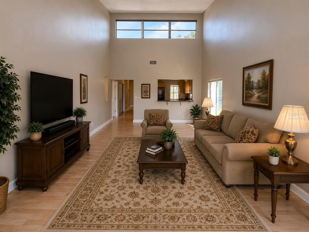 A hallway with light wood-look flooring leads toward a kitchen with a breakfast bar — 118 DAHLIA VILLAGE CIRCLE UNIT 79, ORLANDO, FL