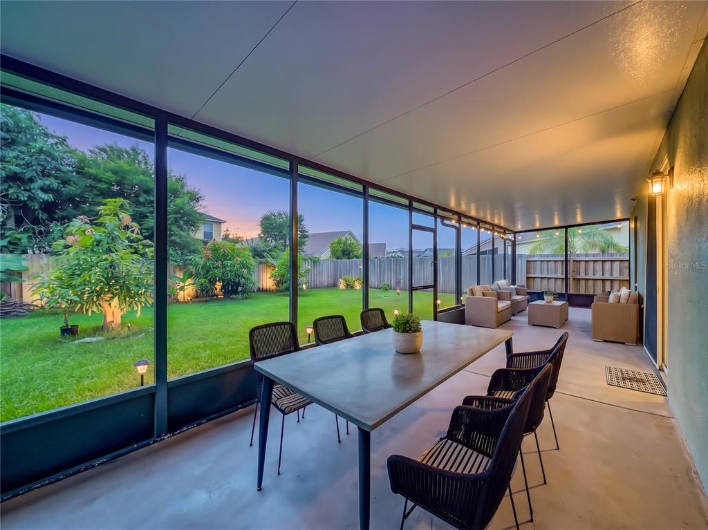A screened-in patio features a dining table, outdoor seating, and a view of the backyard — 13556 HAWKEYE DRIVE, ORLANDO, FL