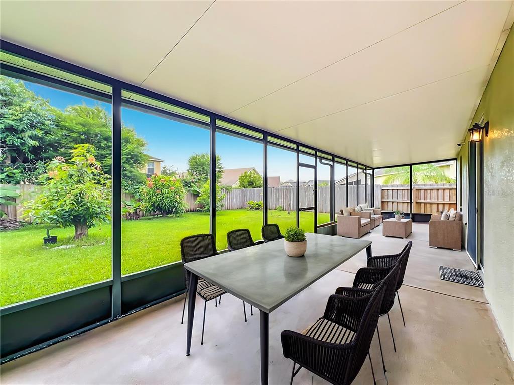 A screened-in patio features a dining table, outdoor seating, and a view of the backyard — 13556 HAWKEYE DRIVE, ORLANDO, FL