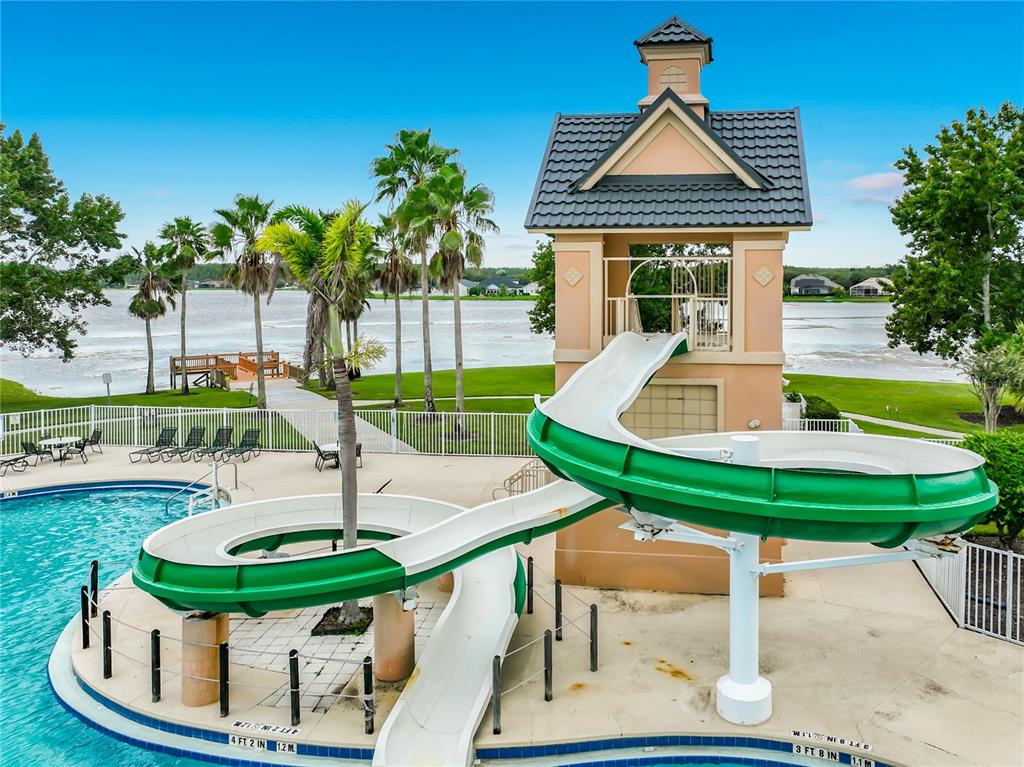 A swimming pool with a green water slide and a small tower structure outdoors — 13556 HAWKEYE DRIVE, ORLANDO, FL