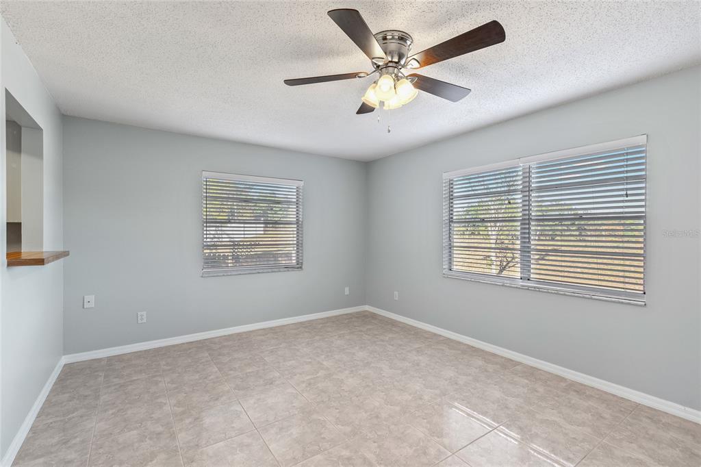 A room with light gray walls, tile flooring, a ceiling fan, and two windows — 2711 N DELLWOOD DRIVE, EUSTIS, FL