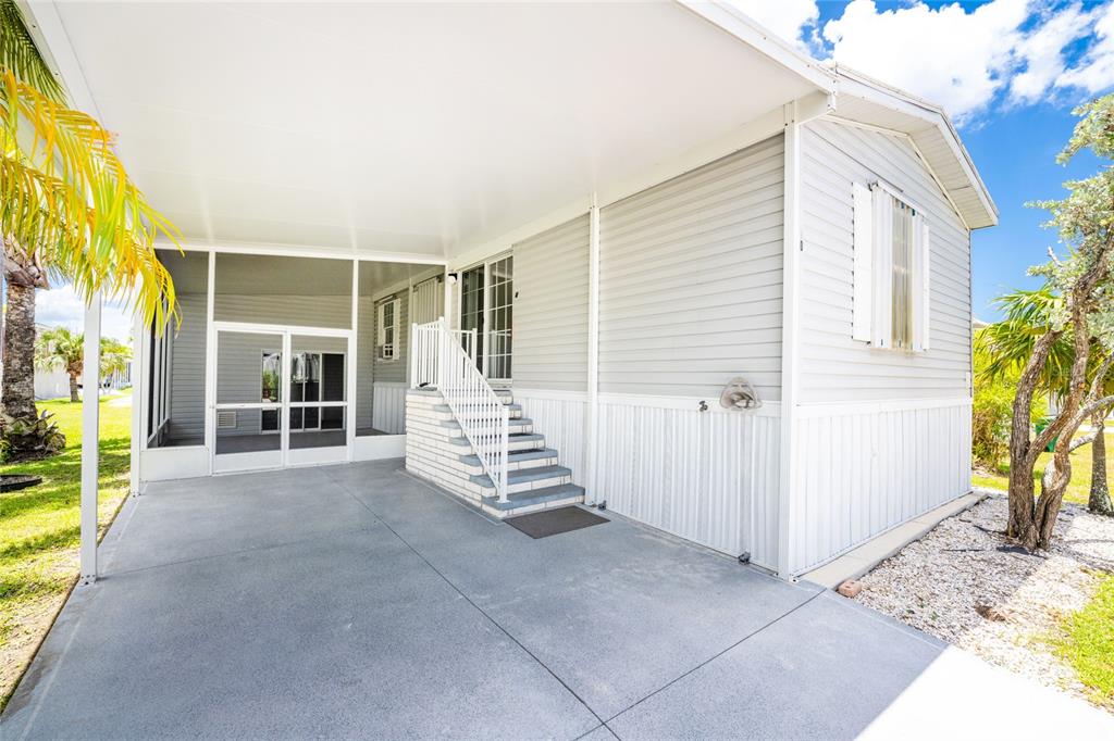 A concrete carport leads to a set of stairs and a screened-in porch area — 10 HOLLAND DRIVE, PUNTA GORDA, FL