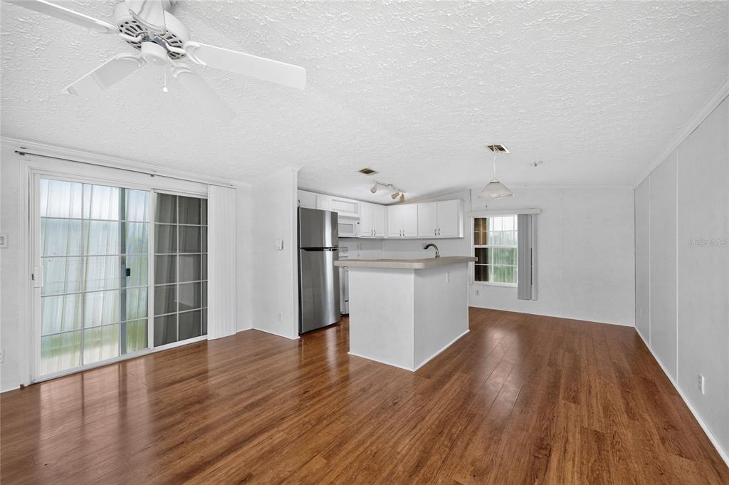 An open-concept kitchen and dining area features white cabinetry, stainless steel appliances, and wood flooring — 10 HOLLAND DRIVE, PUNTA GORDA, FL