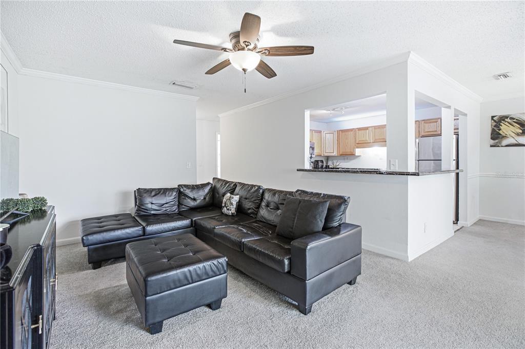 A living room features a black sectional sofa, a matching ottoman, and a kitchen pass-through window — 8880 OLD KINGS ROAD S UNIT 4, JACKSONVILLE, FL